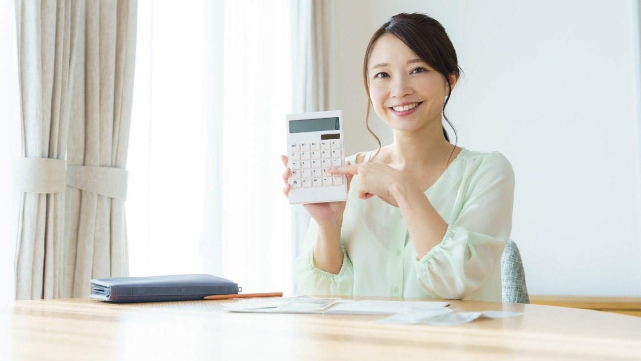 電卓を持ち、家計簿をつける女性。就労移行支援を受けている間は、できるだけ生活費を抑える意識も大切です。