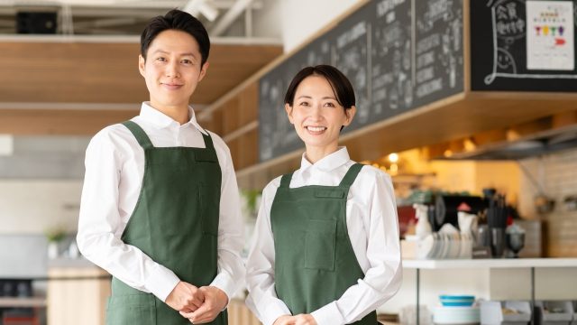エプロンを付け、カフェで働く男女の写真。就労継続支援A型事業所の仕事の一例。A型で雇用されると、一般就労が困難な障がいや難病のある方が、「福祉的就労」という形で働けます。