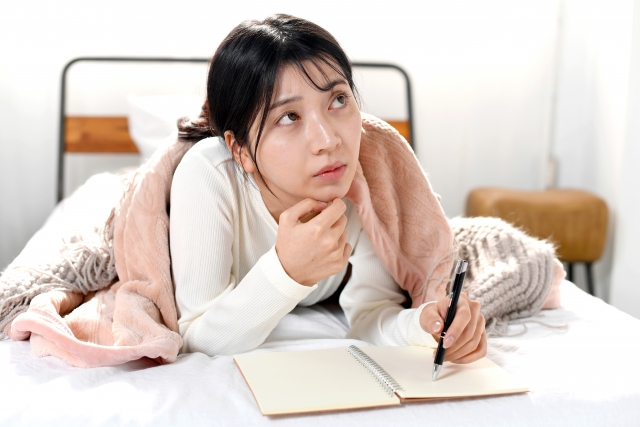 ノートを開いた女性が予定を立てている画像