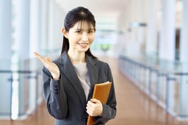 ノートを持った女性が案内をしている画像