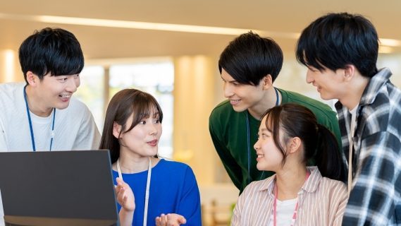 就労継続支援A型事業所の仕事の一例。パソコンでの仕事をしながら会話をする男女５名の写真。