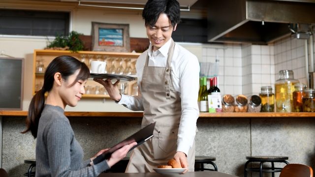 就労継続支援A型のカフェで働く男性の写真。エプロンを付けてオーダーをとっています。就労継続支援A型では比較的低いハードルで働きやすい傾向があります。