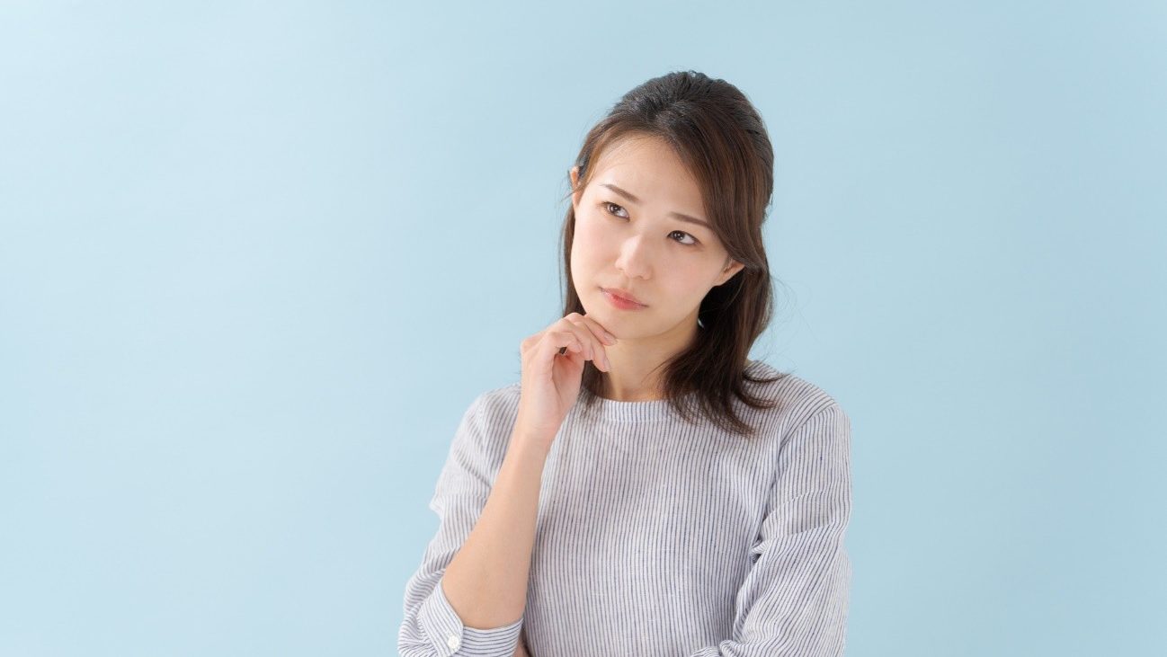 手を顔に添えて悩む女性の写真。就労継続支援A型を選択する際、メリット、デメリットとは何でしょうか。
