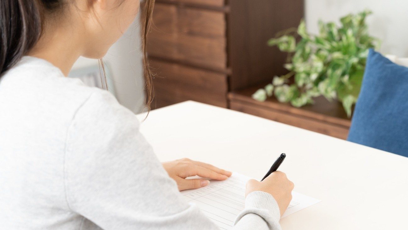 履歴書を書く女性の後ろ姿。就労継続支援A型に応募する際には、履歴書の提出が求められます。