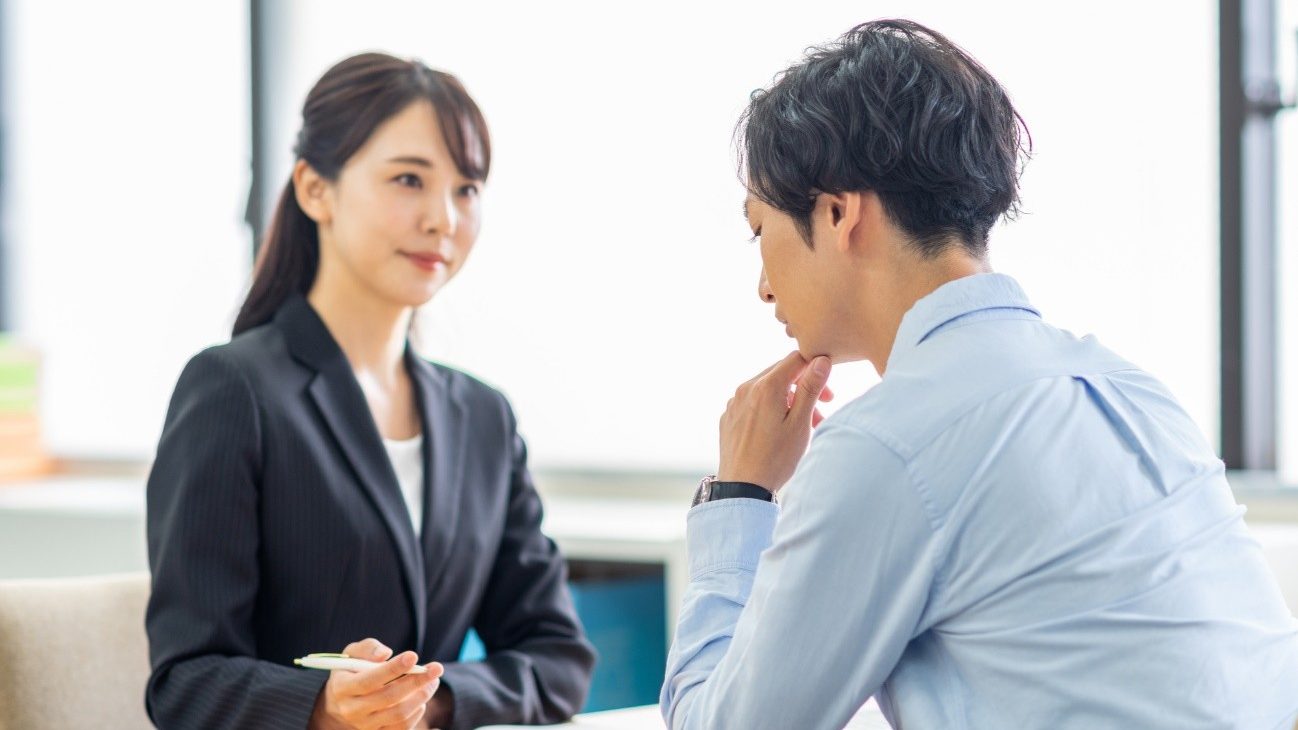 相談をする男性と相談を受ける女性の写真。就労定着支援では就職後の定着を企業と利用者の間で支援する。就職後の悩みの解消と、働きやすい環境づくりをサポートする。