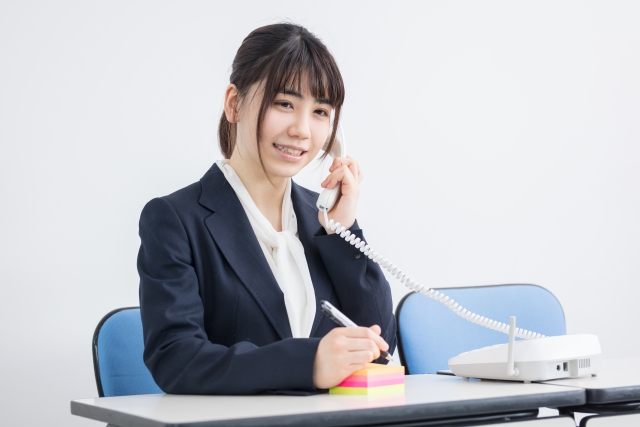 メモを取りながら電話をする女性の画像
