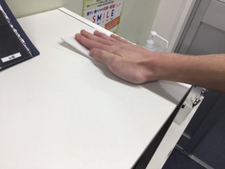 掃除中、男性が棚の上をアルコール除菌している様子。