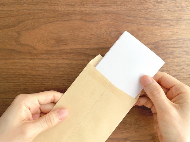書類を封筒に入れる手元の画像