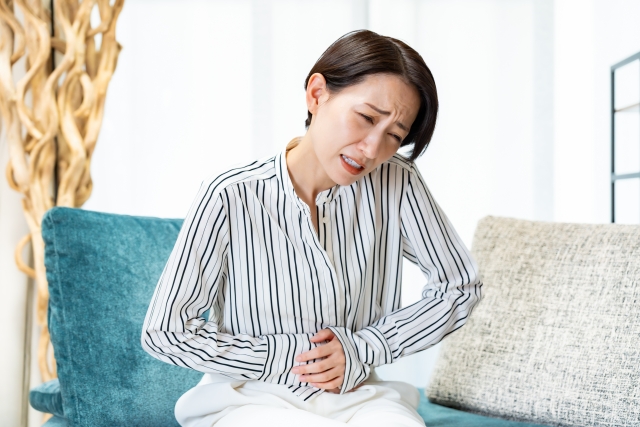 お腹を押さえる女性の画像