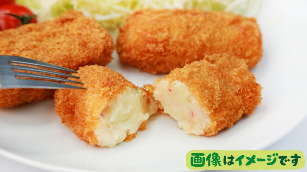 白い皿に俵形のクリームコロッケが３つ置かれている。3つの内1つは半分に割れていて断面が見えている。