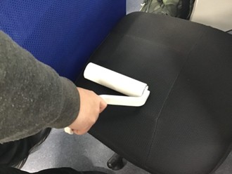 男性が椅子に掃除用具のコロコロを使っている様子。