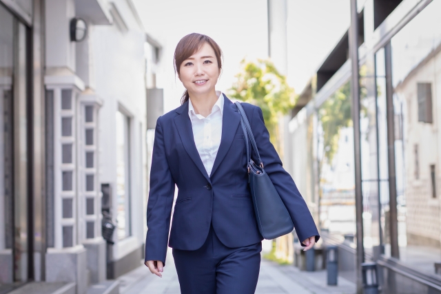 外を歩くスーツを着た女性の画像