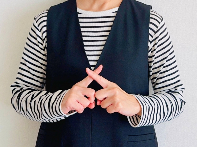 バツマークをする女性の画像