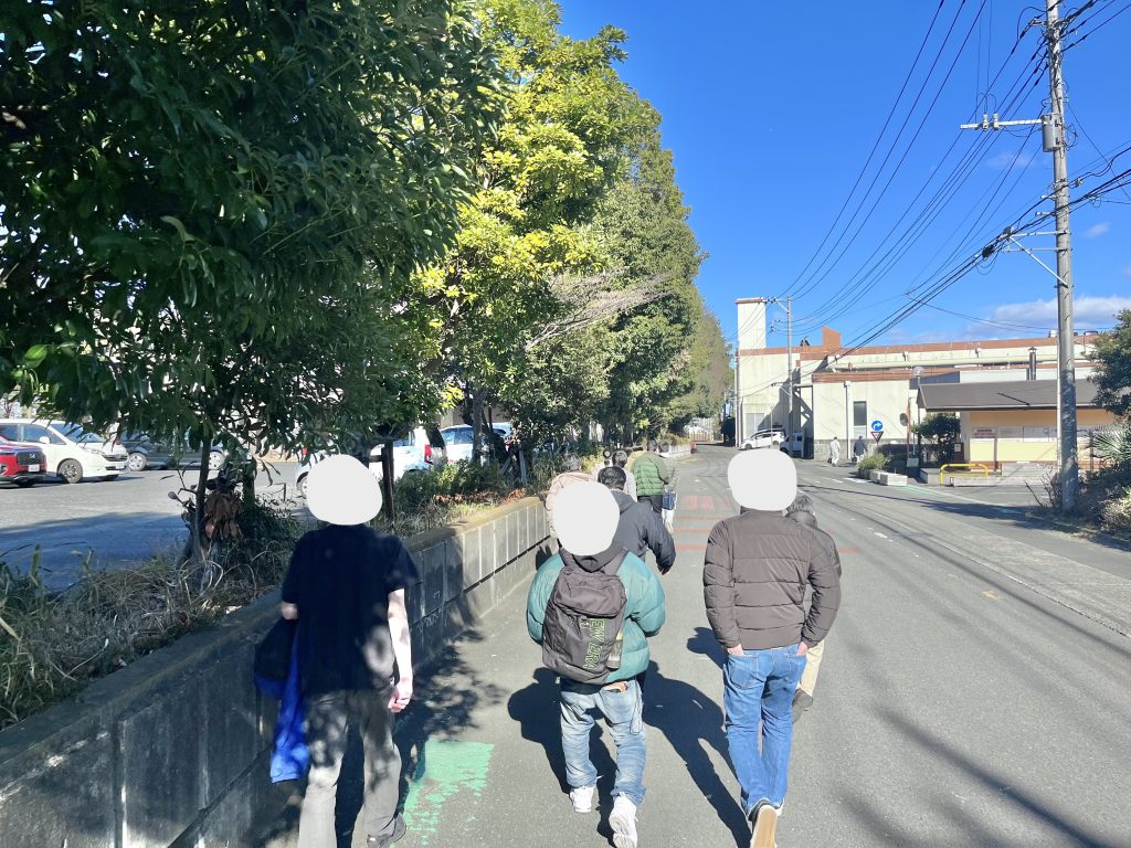 快晴の下で利用者が歩く様子。左側には木々が並んでいる。