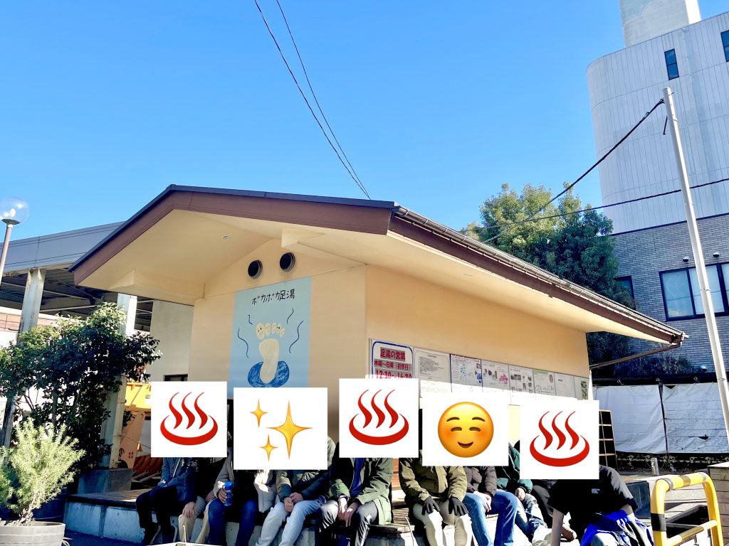 ポカポカ足湯。快晴の下、利用者が足湯のふちに腰かけている集合写真。