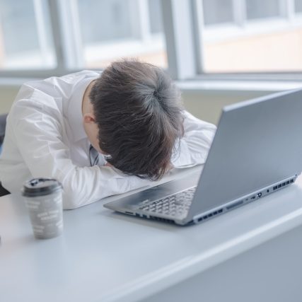 机に伏せる男性の画像